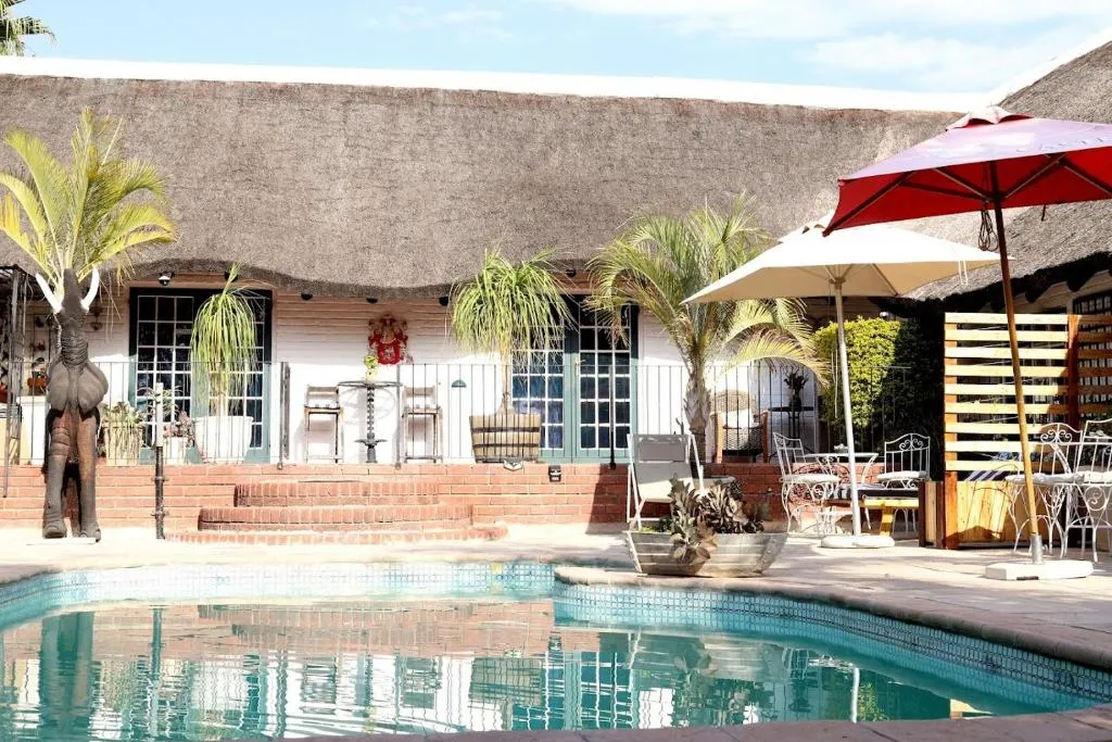 The thatched main house behind the swimming pool