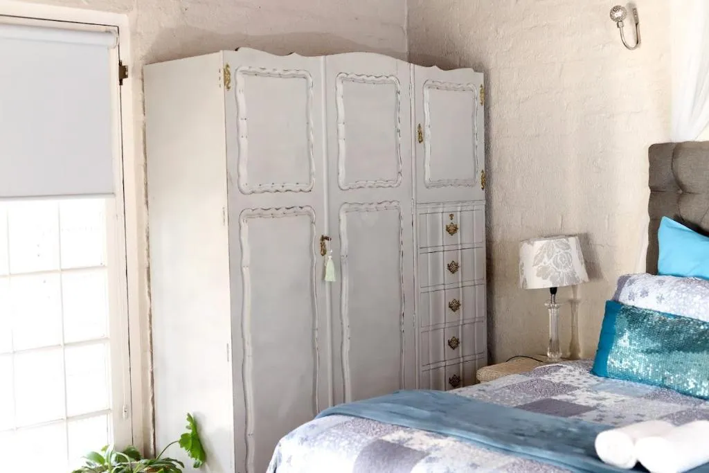 Antique painted wardrobe beside the bed
